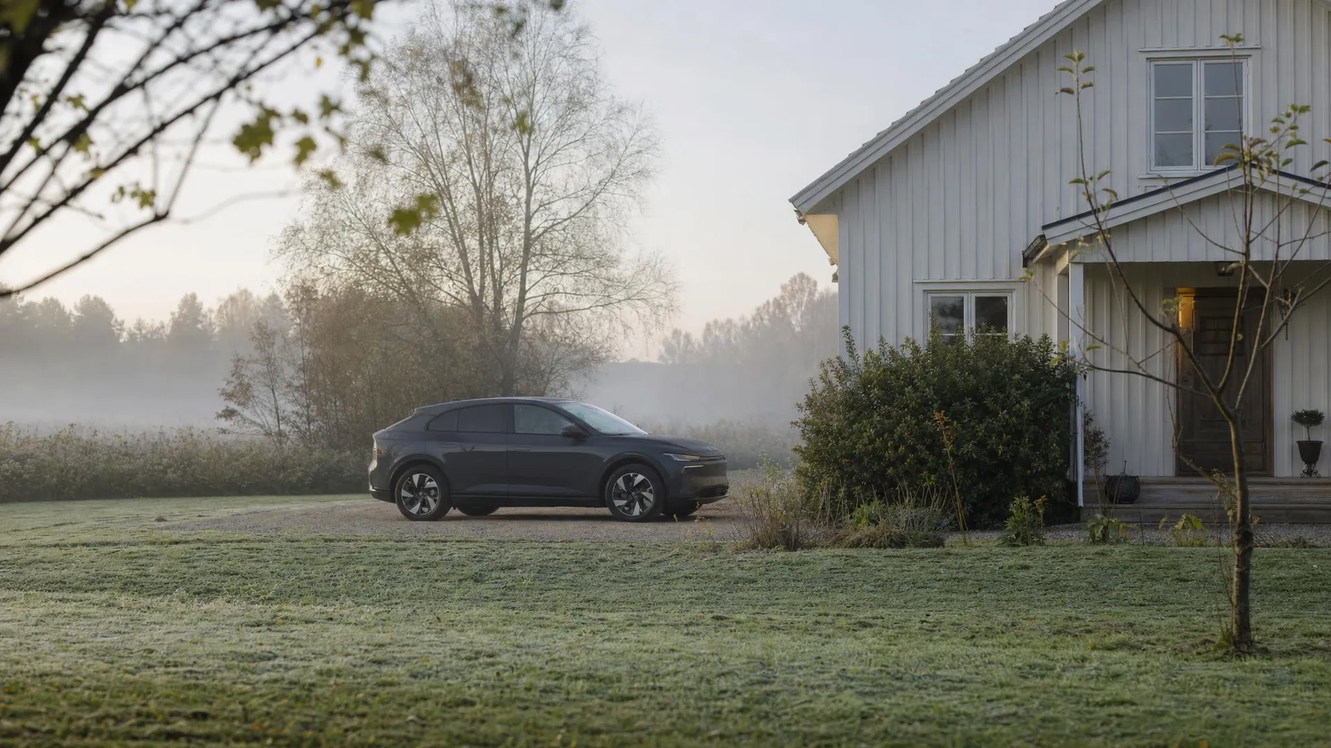 Elbil som står parkerad framför ett hus en tidig morgon