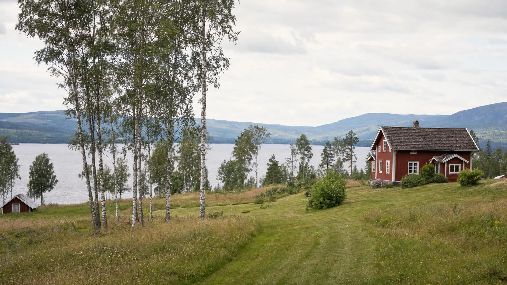 Dalalandskap med röd gård, björkdunge och sjö i Dalarnas län