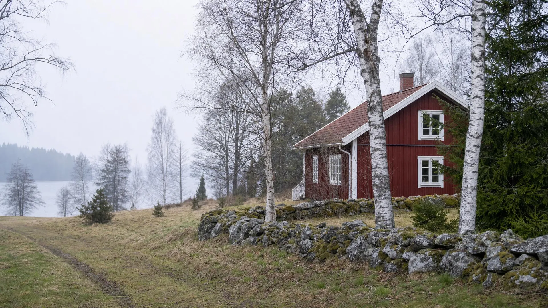 Skogs- och sjölandskap med rött hus och stengärdsgård i Kronobergs län