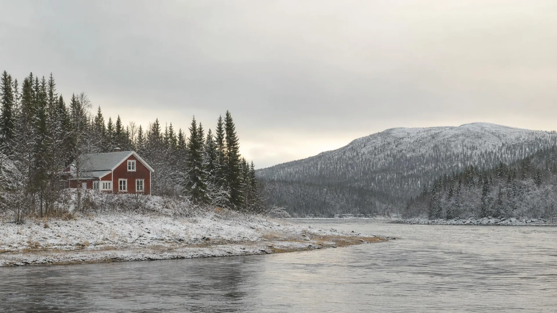 Norrbottniskt landskap med rött hus, skog och älv i Norrbottens län