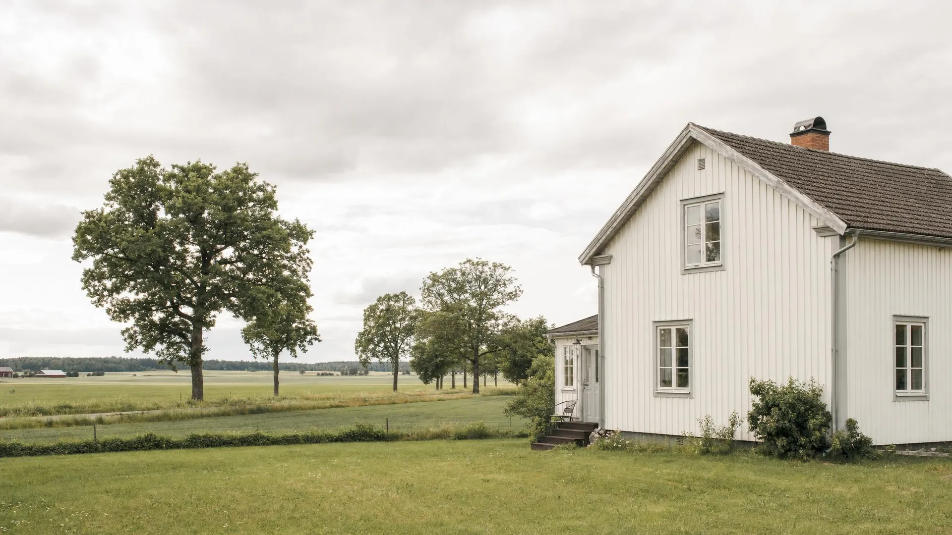 Östgötaslätt med vit gård, åkrar och ekar i Östergötlands län