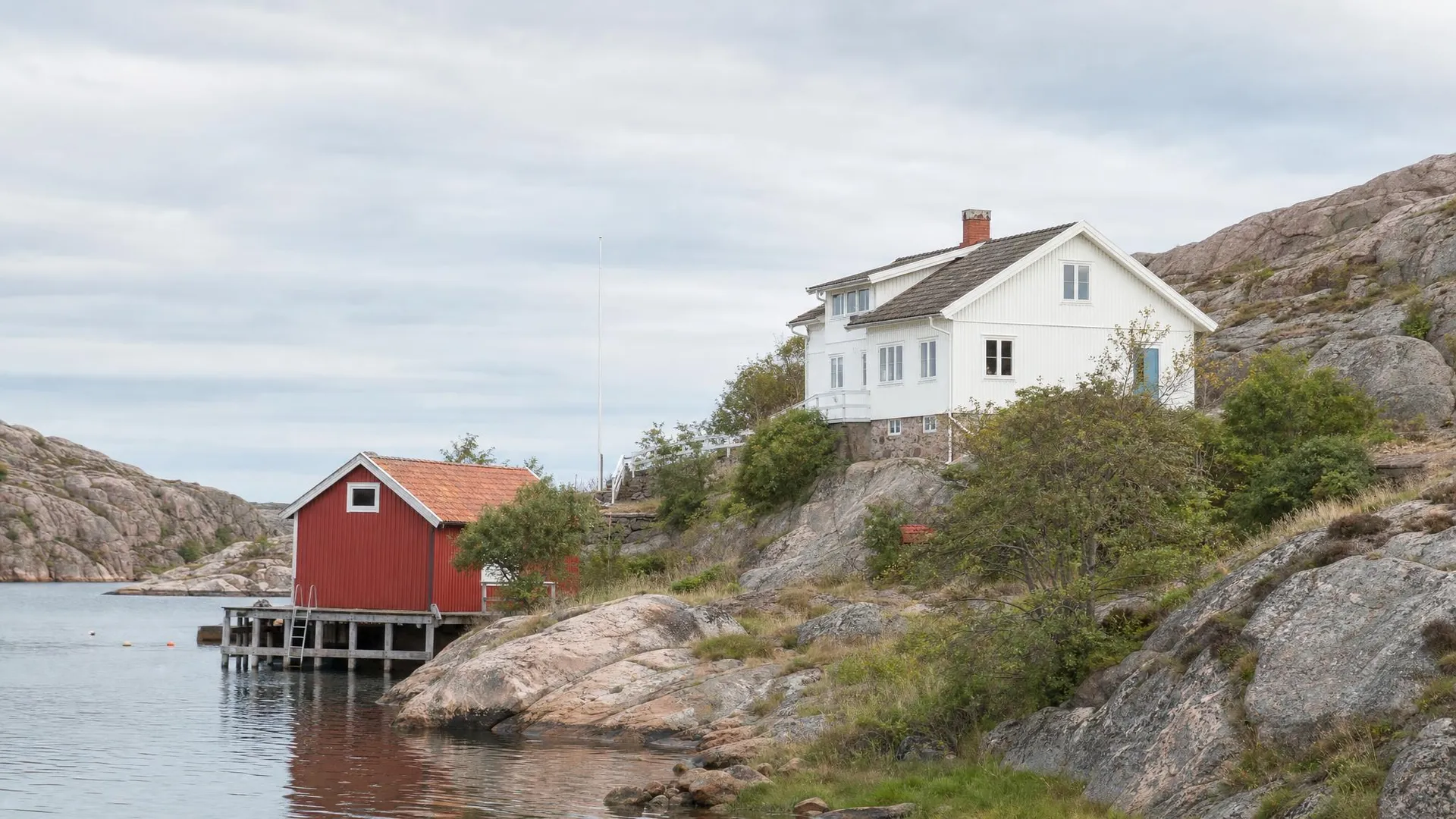Bohuslänsk kust med rosa granit, vitt trähus och sjöbod i Västra Götalands län